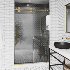 a black and white tiled bathroom with gold trim on the shower door, sink and mirror