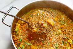 a ladle full of soup is being held by a spoon