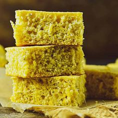 three pieces of yellow cake sitting on top of a wooden table next to sliced bananas