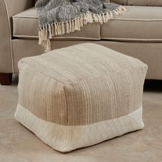 a beige ottoman sitting on top of a tiled floor