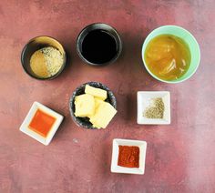 four bowls with different types of food in them on a brown table next to some sauces and condiments