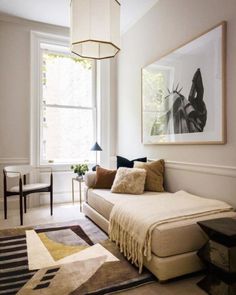 a living room filled with furniture and a painting hanging on the wall next to a window