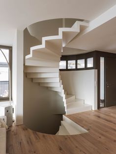 a spiral staircase in the middle of a living room next to a couch and window