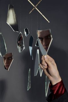 a person holding a knife in front of a mirror with mirrors hanging from it's sides