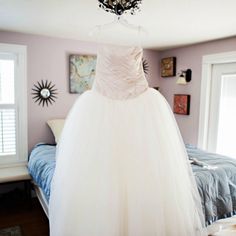 a wedding dress hanging on a bed in a bedroom