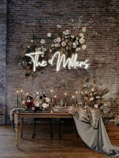 a table with candles and flowers on it in front of a brick wall that says the millers