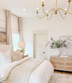 a bedroom with white bedding and neutral decor, including a large chandelier