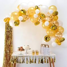 a party table with balloons and confetti on the table, along with gold tassels