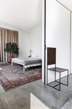 a bed sitting on top of a rug next to a chair and table in a room