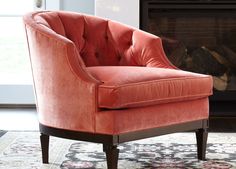 an orange chair sitting in front of a fire place with a rug on the floor