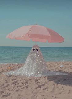 an umbrella that is sitting in the sand at the beach with eyes drawn on it