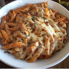 a white bowl filled with pasta covered in cheese