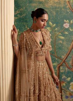 An exquisite gold net lehenga set is a stunning ensemble that features a intricately embroidered lehenga that adds a touch of opulence to your ethnic look. The accompanying elbow sleeves net blouse complements the lehenga beautifully, creating a perfect blend of tradition and contemporary style. The overall allure of the outfit is enhanced with a detailed embroidered net dupatta. It is a must-have for the brides and festive occasions. This lehenga set is a timeless masterpiece that effortlessly Indian Bridal Lehenga Designer, Gold Lehenga, Ridhi Mehra, Net Blouse, Reception Outfit, Organza Lehenga, Net Blouses, Indian Bridal Lehenga