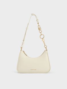 This product is made with at least 20% sustainable materials by weight. CHARLES & KEITH uses recycled, degradable, organic, and water-based materials in our eco-conscious collection.For a minimalist yet striking bag, look no further than this versatile cream trapeze bag. Featuring a sleek silhouette with soft rounded corners, this piece offers ample space that can easily hold your everything essentials and more. Complete with a shiny gold-toned chain featuring a lock and key detail, it will cert Charles And Keith Bags, Charles And Keith, Trapeze Bag, Neutral Bag, Brand Name Bags, Cream Bags, Chalk Bags, Latest Bags