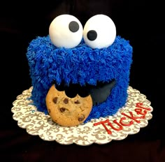 a cookie monster cake with eyes and a cookie