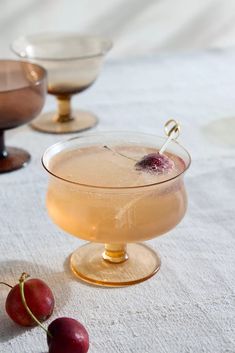 two cherries are sitting on the table next to some glasses with drinks in them