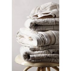 stack of folded towels sitting on top of a stool