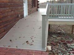 a white bench sitting on the side of a building next to a wooden fence and brick walkway