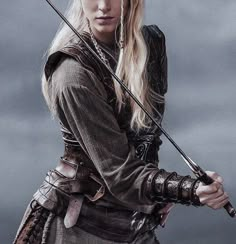 a woman with long blonde hair holding two swords in her hands and looking at the camera