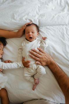 a man and woman laying in bed with a baby on top of it's back