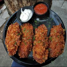 some fried food on a black plate with sauce and ketchup in the middle