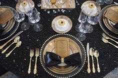 the table is set with black and gold place settings