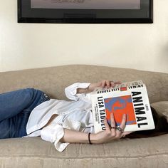 a woman laying on top of a couch reading a book