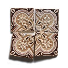 four square tiles with floral designs on the top one is brown and white, while the other is gold