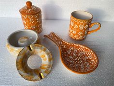 an orange and white porcelain tea set on a table