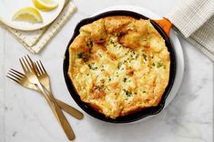 an omelet in a cast iron skillet on a white table with utensils