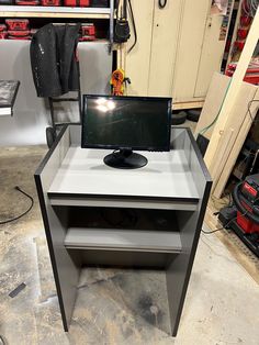 a computer monitor sitting on top of a desk in a room filled with tools and other items