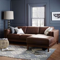 a living room with blue walls and brown leather couch in the corner, along with a rug on the floor