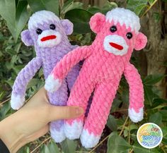 two crocheted stuffed monkeys sitting next to each other in front of some leaves