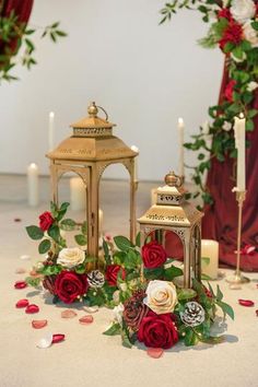 red and white flowers are on the floor next to two small lanterns with candles in them