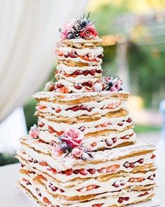 a wedding cake is stacked on top of each other with flowers and berries all over it