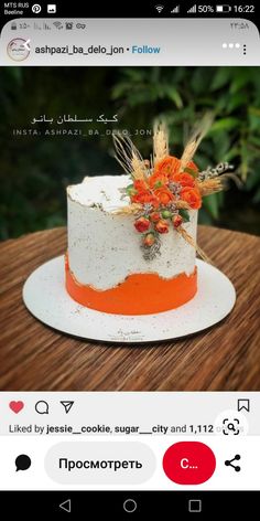 an orange and white cake sitting on top of a wooden table next to a phone