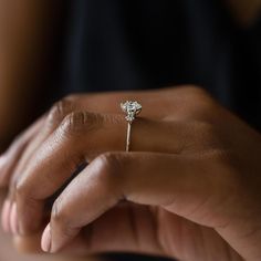 a close up of a person's hand holding a ring with a diamond on it