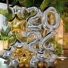 the number twenty five is made out of shiny silver and gold balloons with stars on them