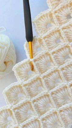 the crochet pattern is being worked on with a knitting needle and yarn ball