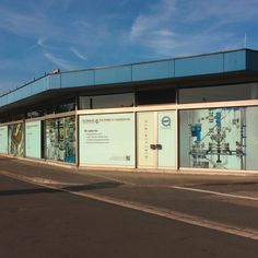 an empty street in front of a building with glass windows and pipes on the side