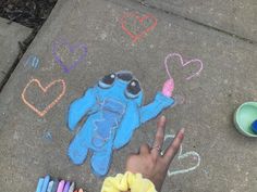 someone is drawing on the sidewalk with chalk and colored crayon pencils in front of them