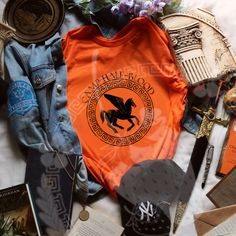 an orange shirt and other items laid out on top of a white sheet with flowers