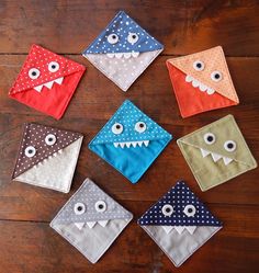 six different colors of cloth with eyes and teeth on them, all in the shape of an envelope