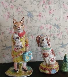 two figurines of cats sitting on top of a table