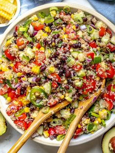 a bowl filled with salad next to corn and avocado slices on the side