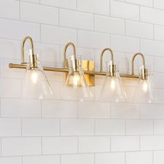 a bathroom light fixture with five lights on it's side and white brick wall in the background