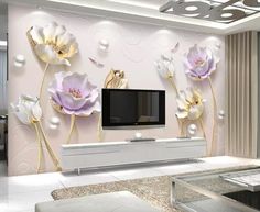 the living room is decorated in white and gold with flowers on the wall, as well as a flat screen tv