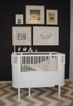 a white crib in a room with pictures on the wall and paintings above it