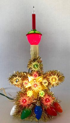 a lighted christmas tree with red, yellow and green lights on it's top