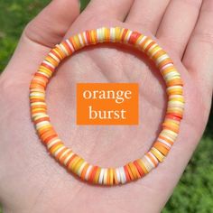 a hand holding a bracelet with orange and white stripes on it that says orange burst